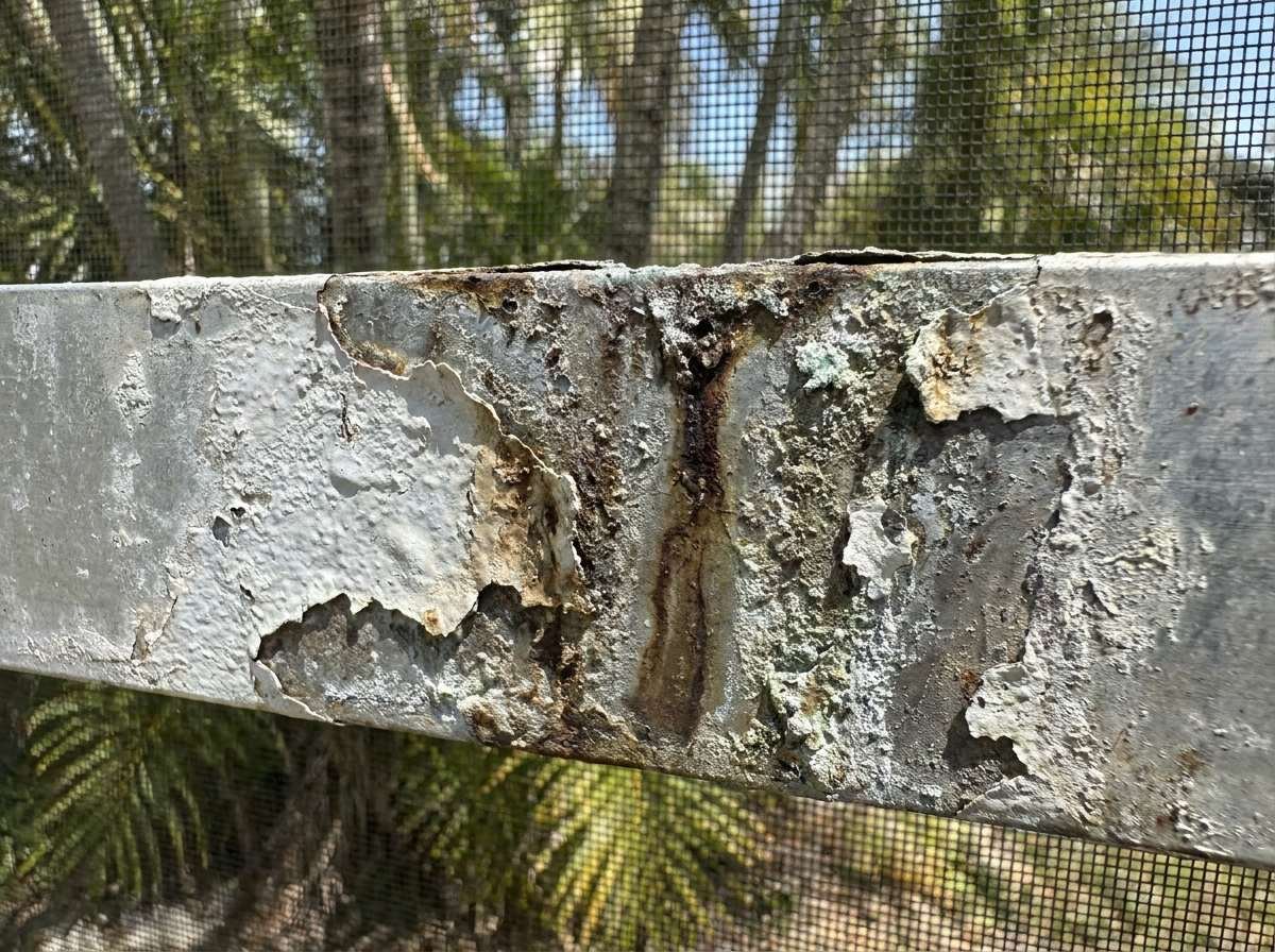 Close-up of a rusted corroded aluminum pool cage beam needing paint restoration in South Florida