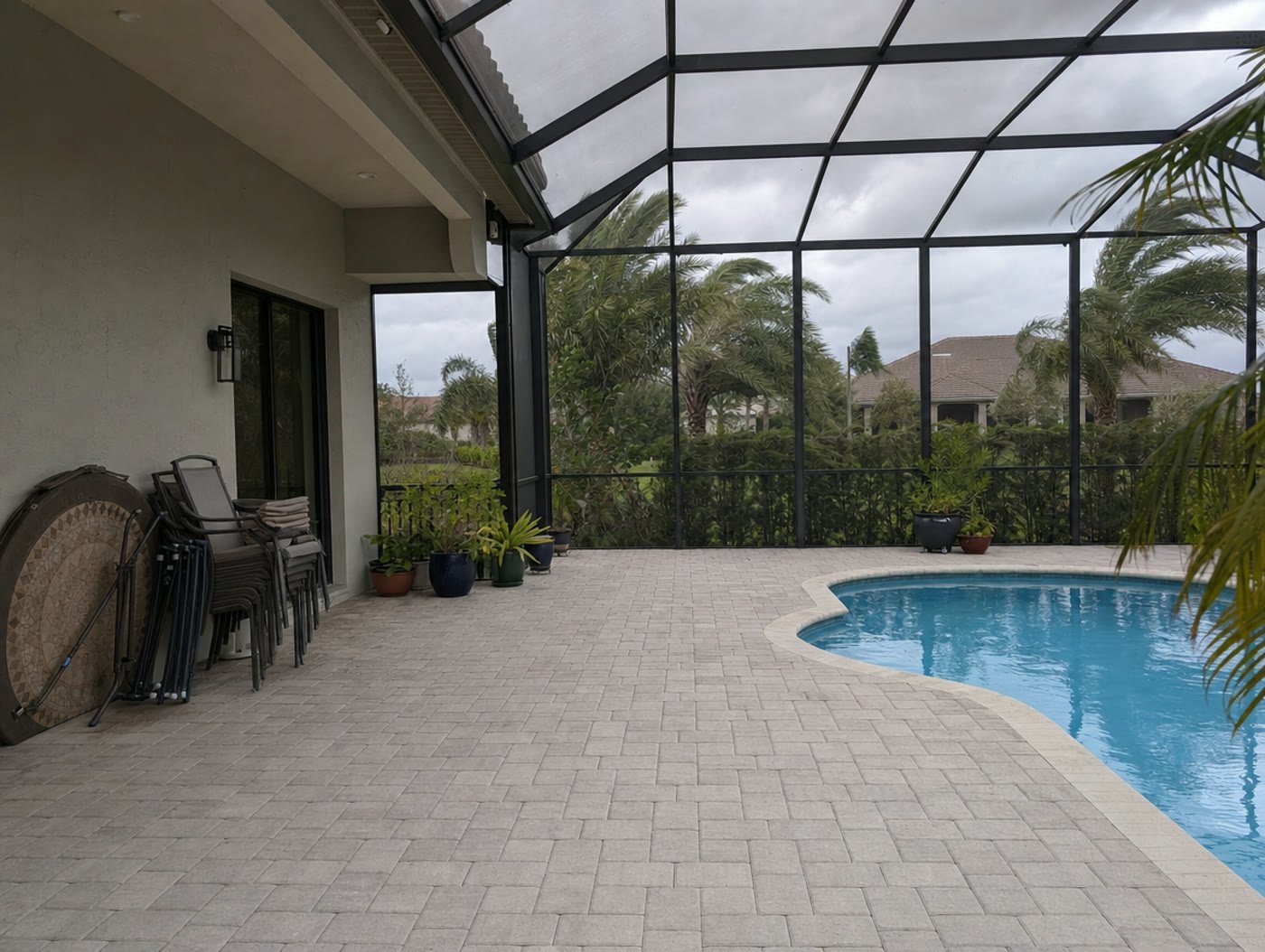 Pool deck inside a screen enclosure cleared of furniture ahead of a Florida hurricane