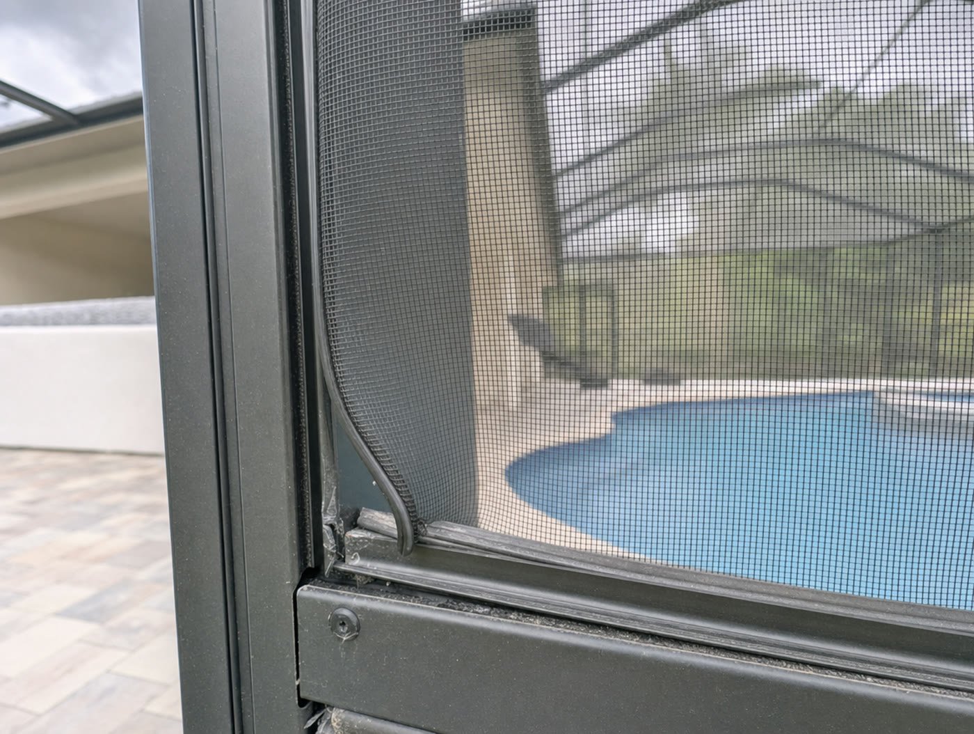 Loose screen panel with spline lifting out of the channel on a Florida pool cage