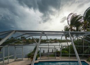 South Florida pool cage screen enclosure under a dark approaching hurricane storm sky
