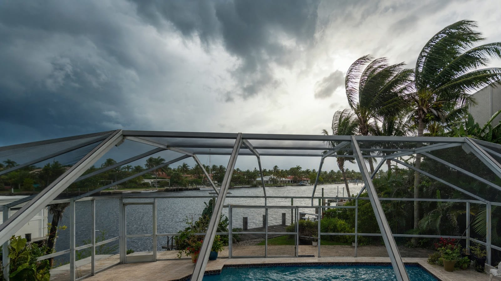 South Florida pool cage screen enclosure under a dark approaching hurricane storm sky