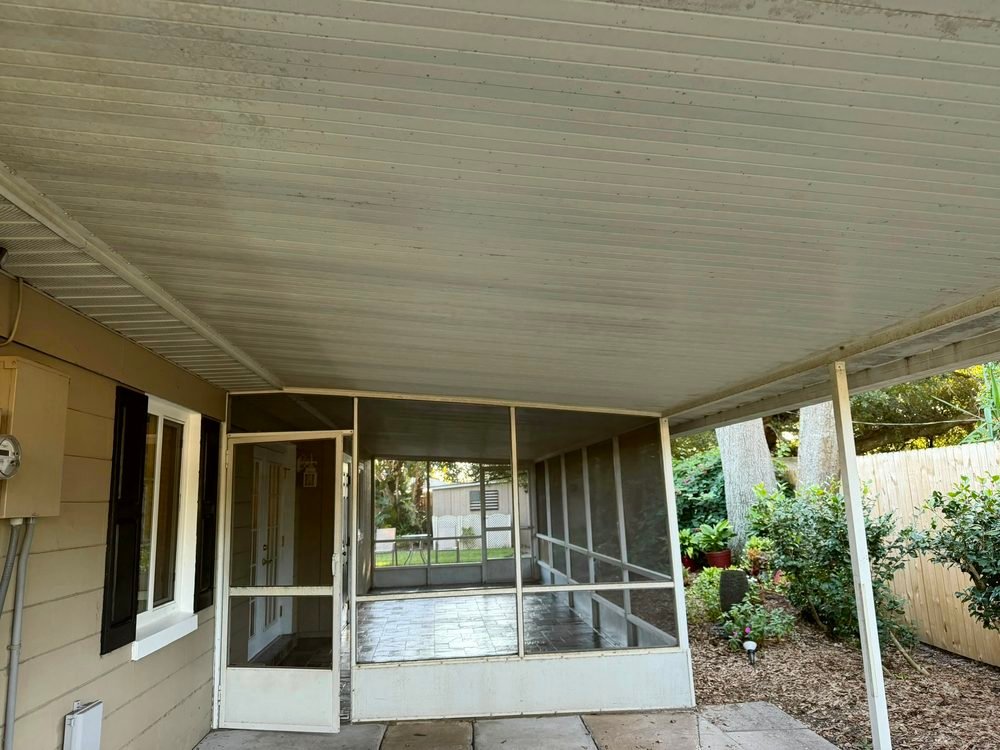 Screen porch with a white aluminum frame and a white screen door before repainting