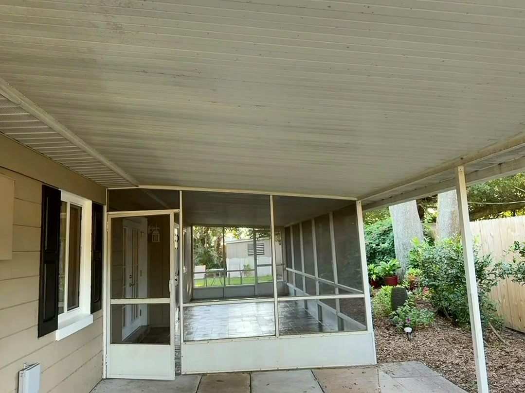White screen door and white aluminum frame on a covered porch, with a solid kickplate across the bottom of the door